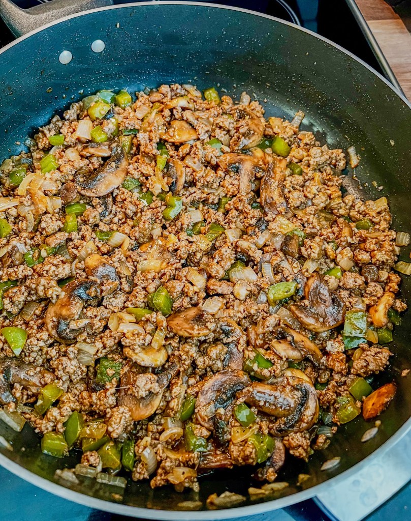 Ground beef, onion, garlic, mushrooms, green pepper, and seasonings in a skillet