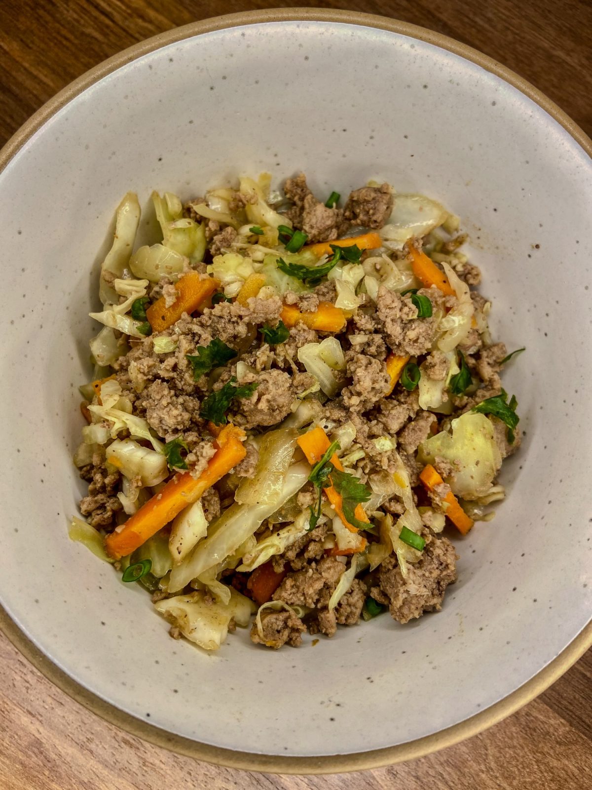 Egg roll bowl in a white bowl on a wooden counter