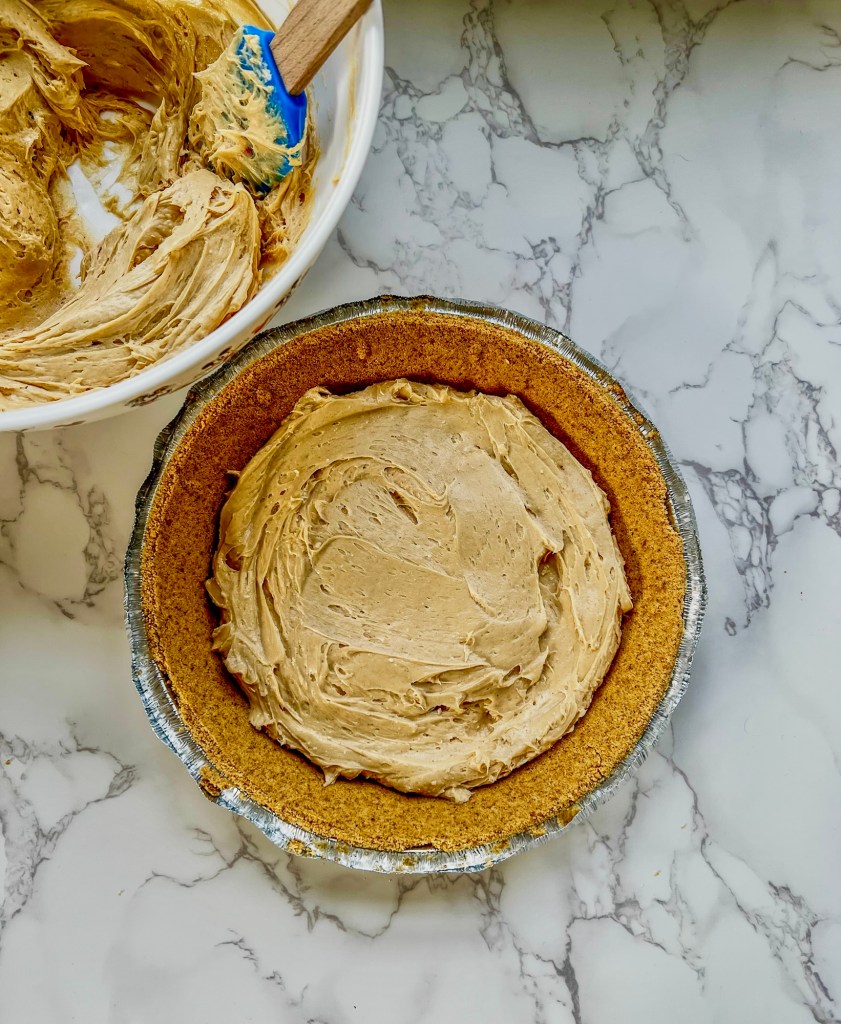 A no bake pie being layered into some graham cracker crust