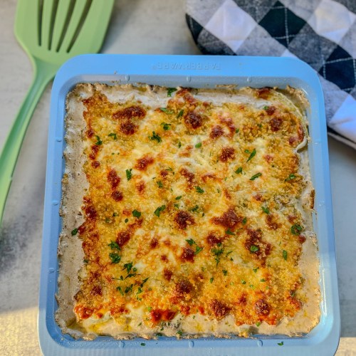 Philly Cheesesteak Casserole in a baking dish with a spatula and oven mit nearby