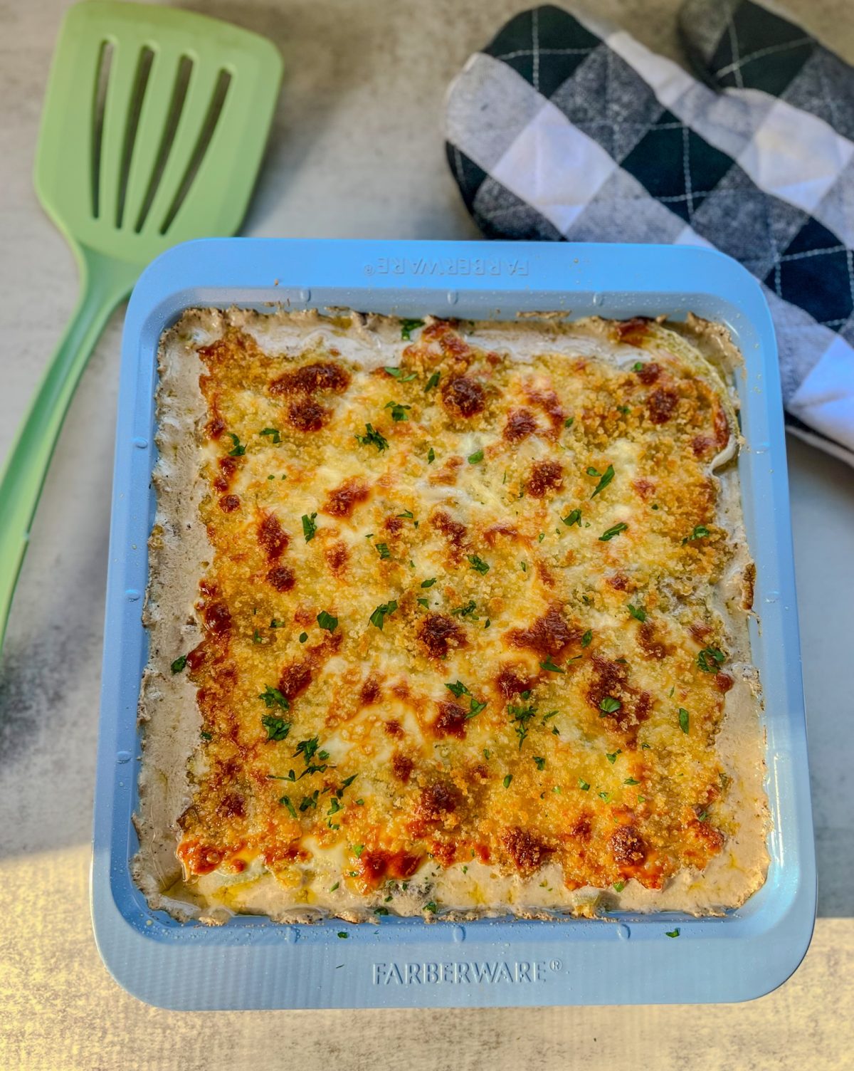 Philly Cheesesteak Casserole in a baking dish with a spatula and oven mit nearby