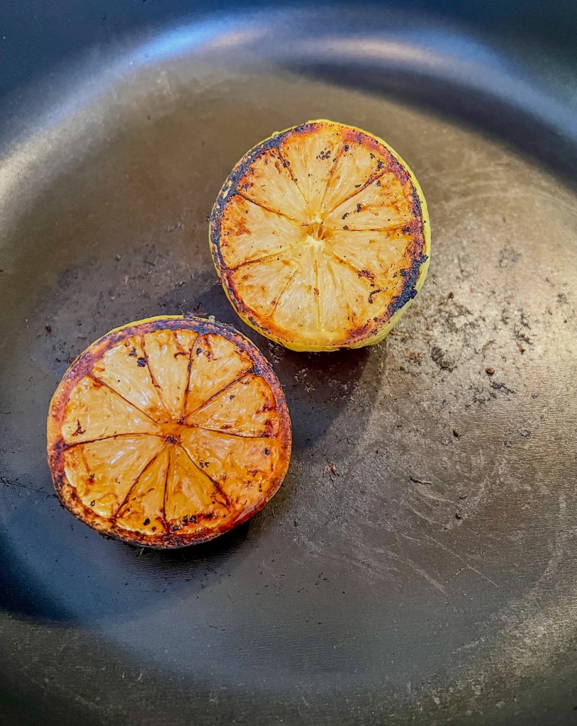 Charred lemon halves in a skillet