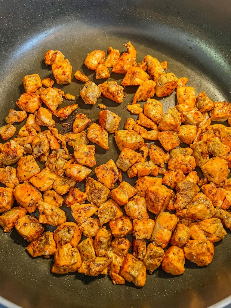 Salmon fillet chunks cooking in a skillet on the stove