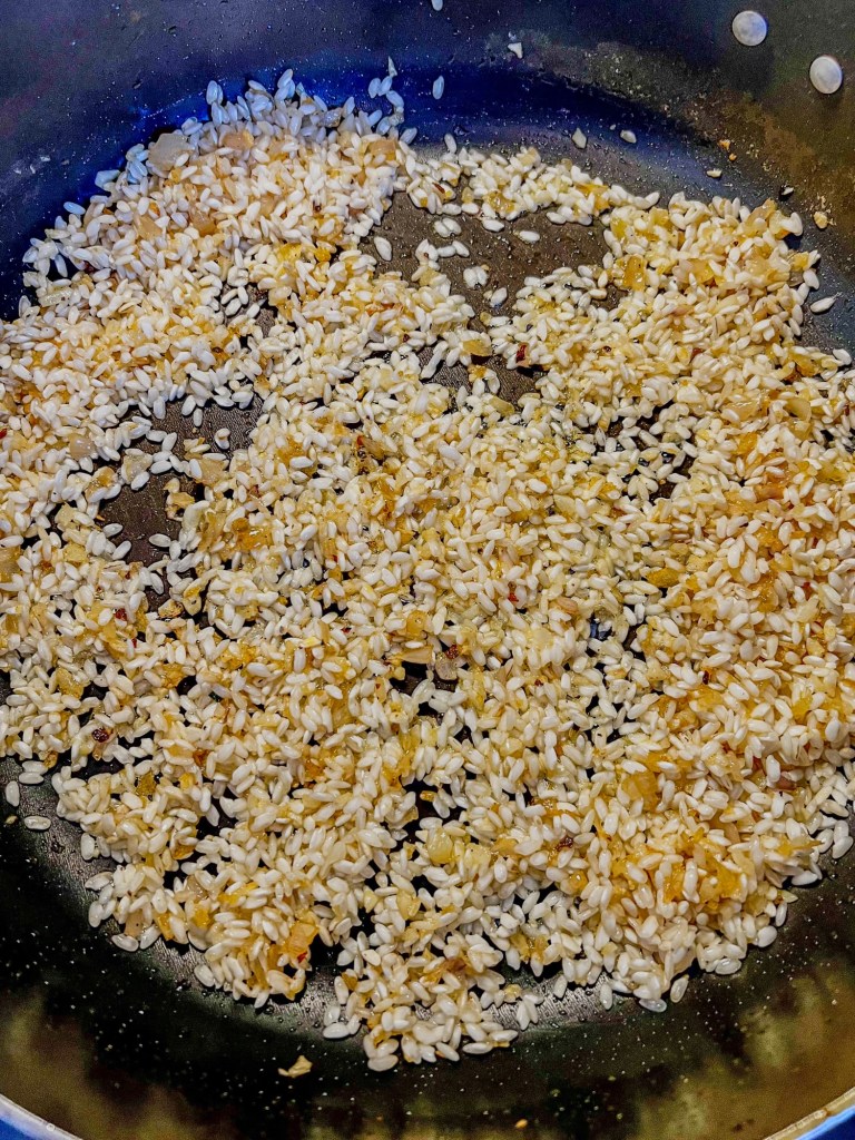 Ingredients cooking in a skillet to make salmon lemon risotto