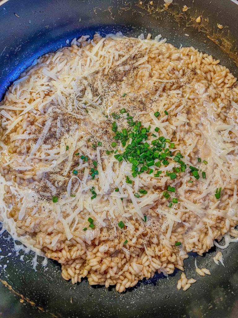 Creamy risotto building in a skillet with some newly added herbs, spices, and cheese
