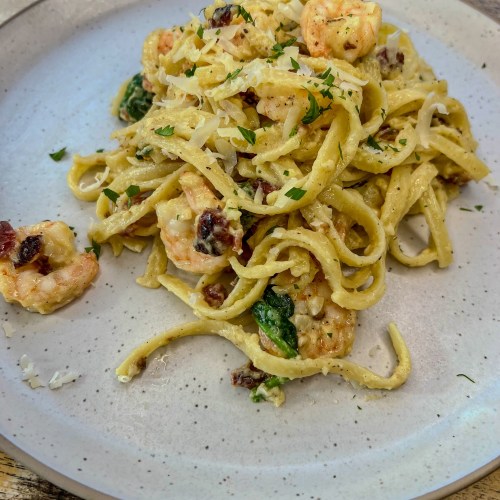 Shrimp carbonara on a white plate on a wooden table