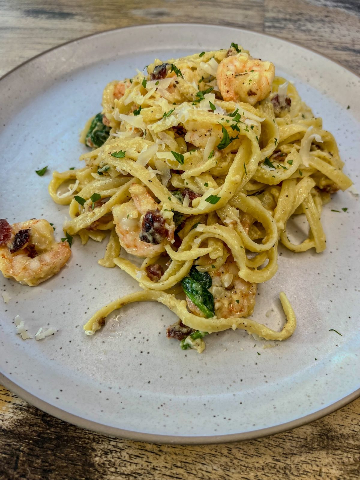 Shrimp carbonara on a white plate on a wooden table
