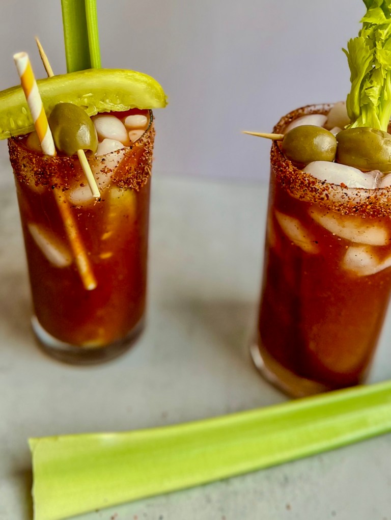 Two Spicy bloody mary drinks with garnishes on a countertop