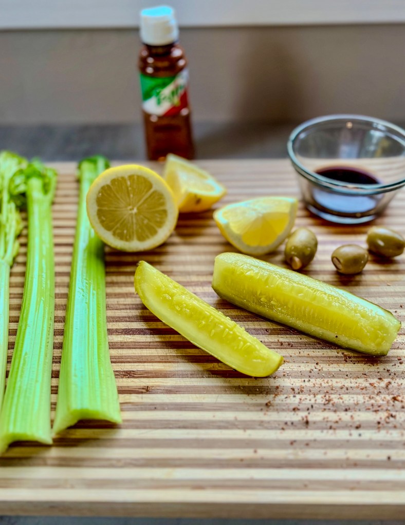 A cutting board with bloody mary garnishes on it on a countertop
