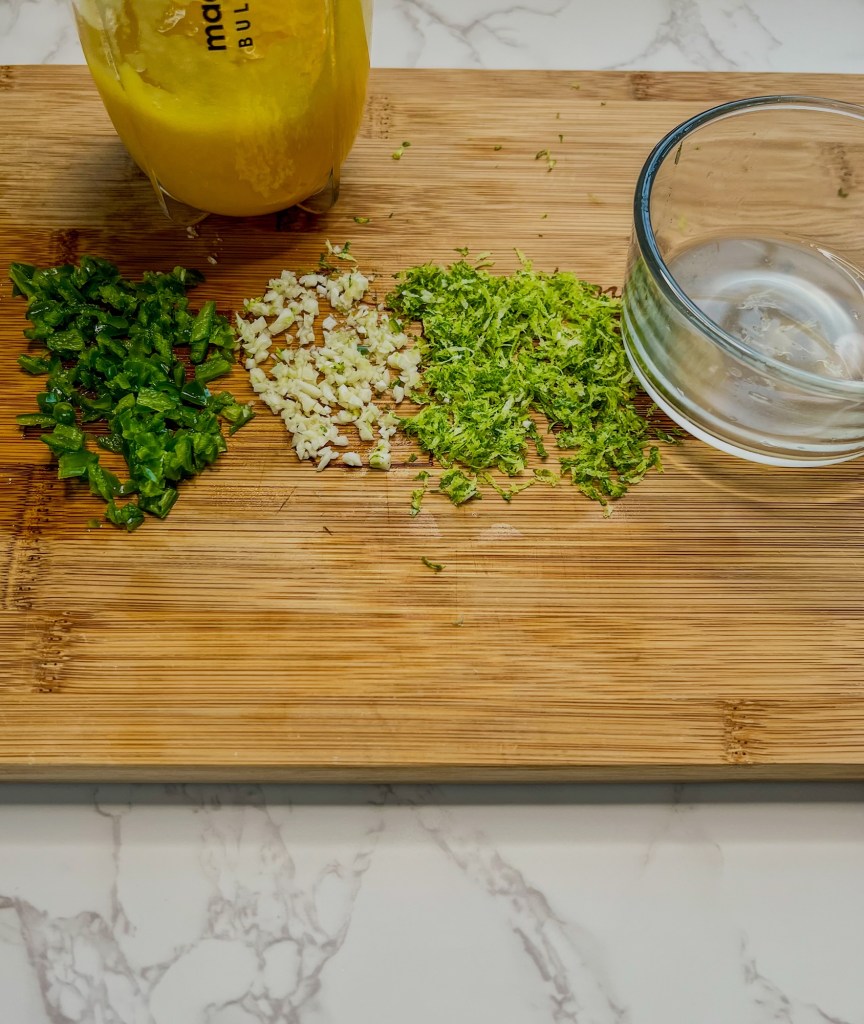 Lime juice, zest, garlic, serrano peppers, and mango purée on a cutting board