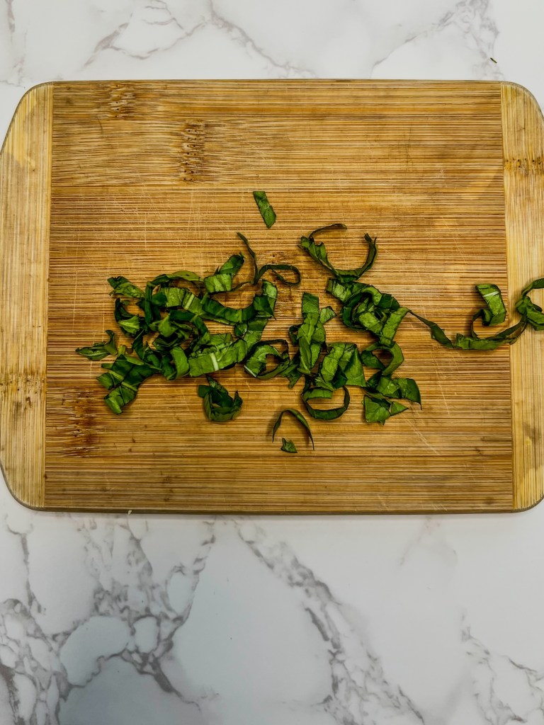 Basil cut into a chiffonade on a cutting board
