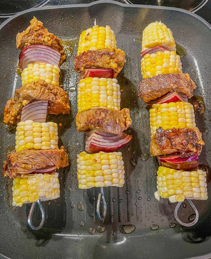 Kabobs cooking in a grill pan on the stove