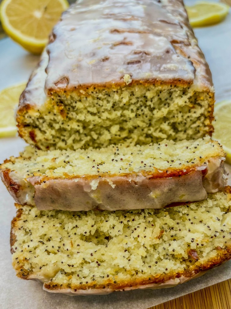 Lemon Poppy Seed Bread that's been iced and sliced, on a cutting board