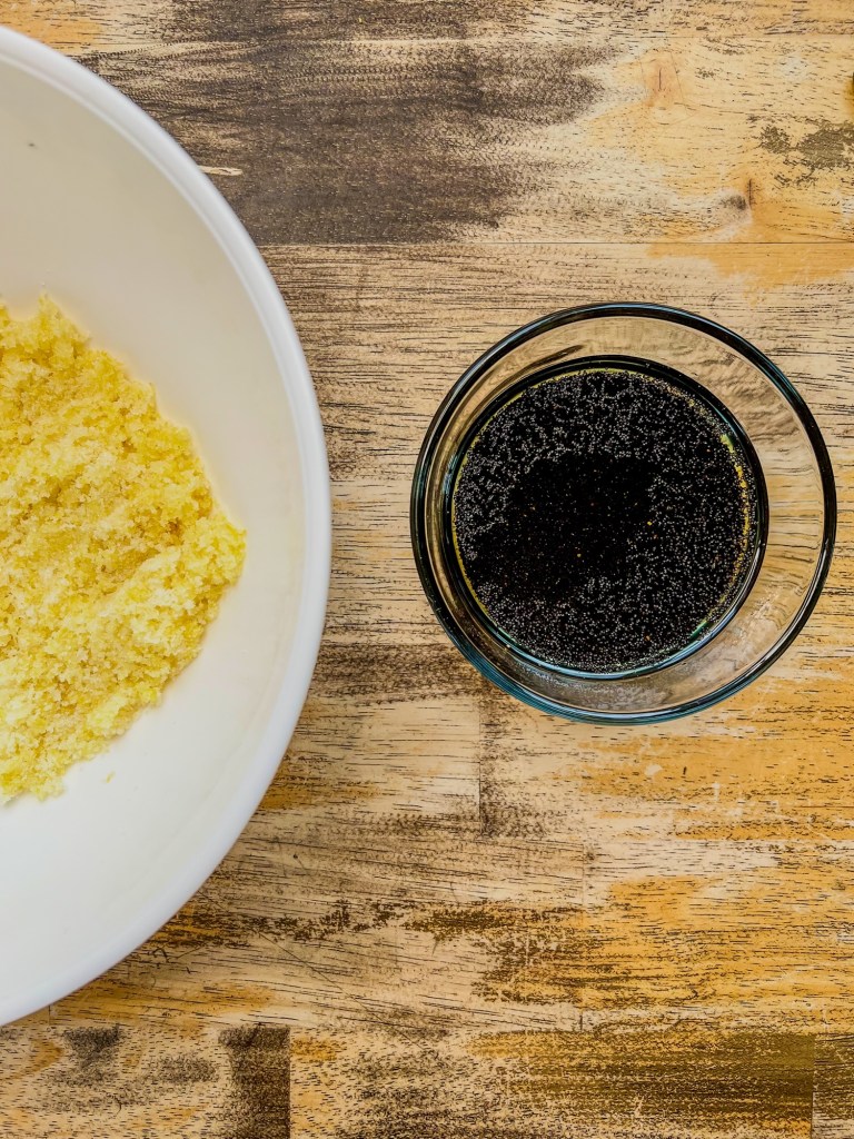 Lemon sugar and poppy seeds blooming in a dish filled with oil, on a wooden table