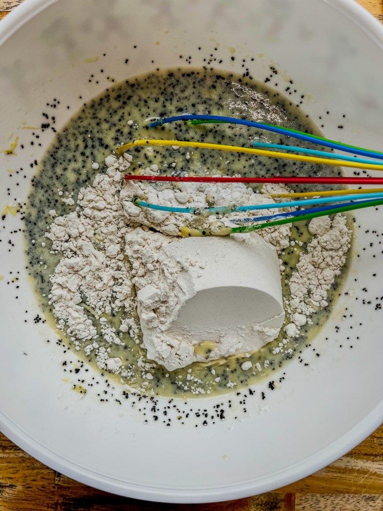 Batter being made in a mixing bowl for triple lemon poppy seed loaf