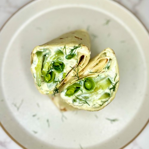 Veggie Wrap with Basil Tzatziki that's been cut in half and garnished with dill on a white plate