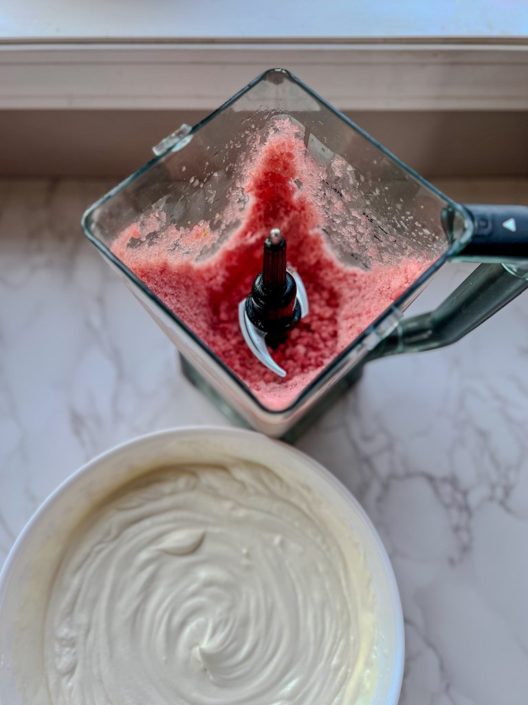 A large bowl of heavy cream next to a large blender full of watermelon slushie mix