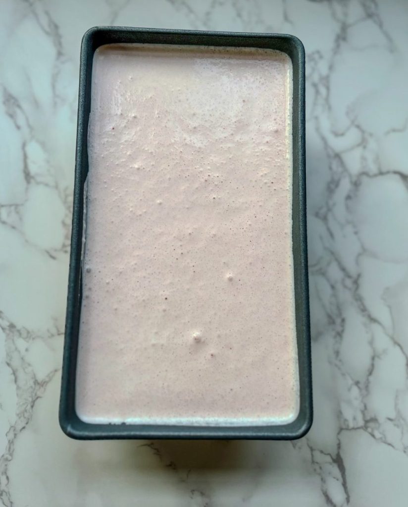 Watermelon Lime Ice Cream in a loaf pan with parchment paper on the top
