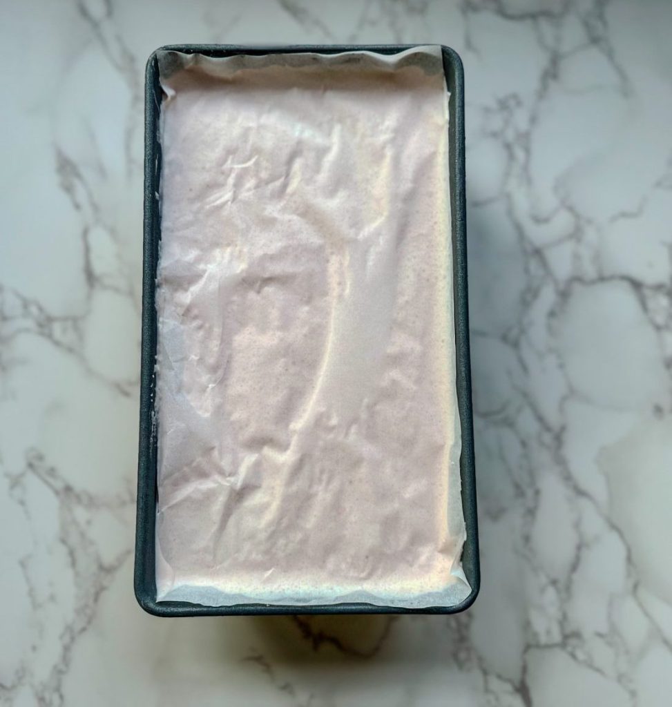 Watermelon Lime Ice Cream in a loaf pan with parchment paper on the top