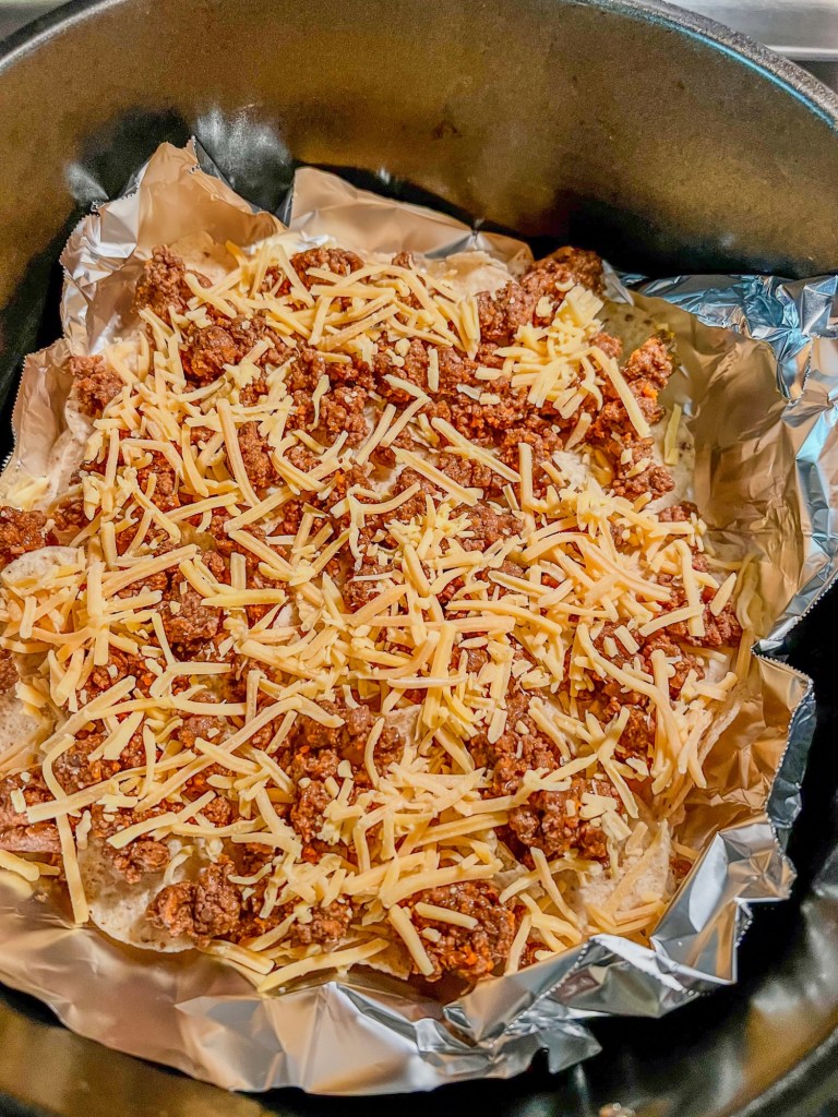 Tortilla chips, cheese, and taco meat in an air fryer basket to make nachos