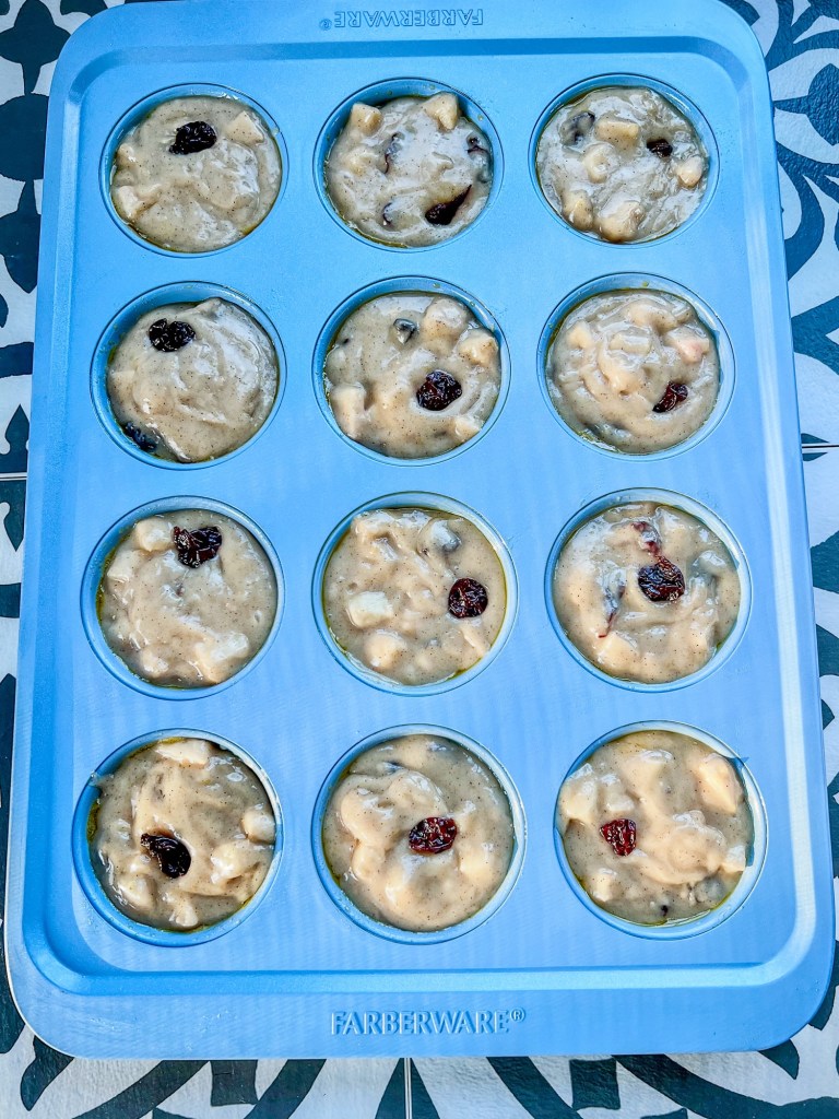 Apple cherry muffin batter in a blue muffin pan before going into the oven
