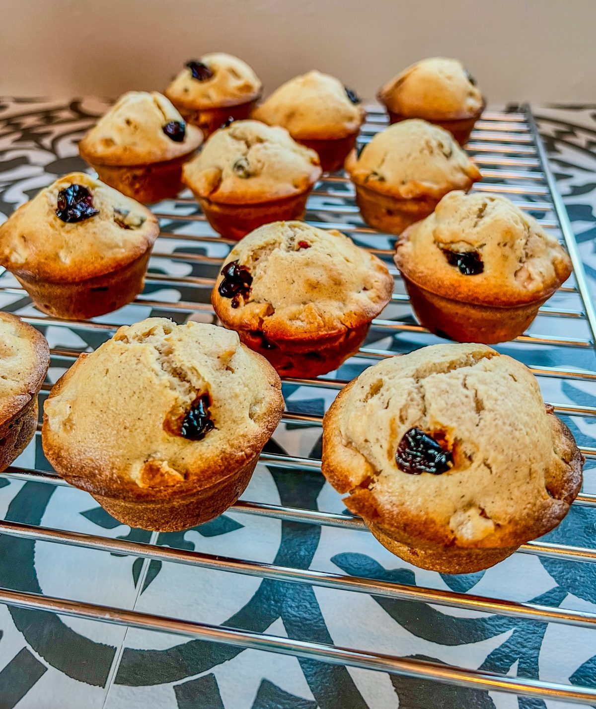 Apple cherry muffins on a cooling rack on a countertop