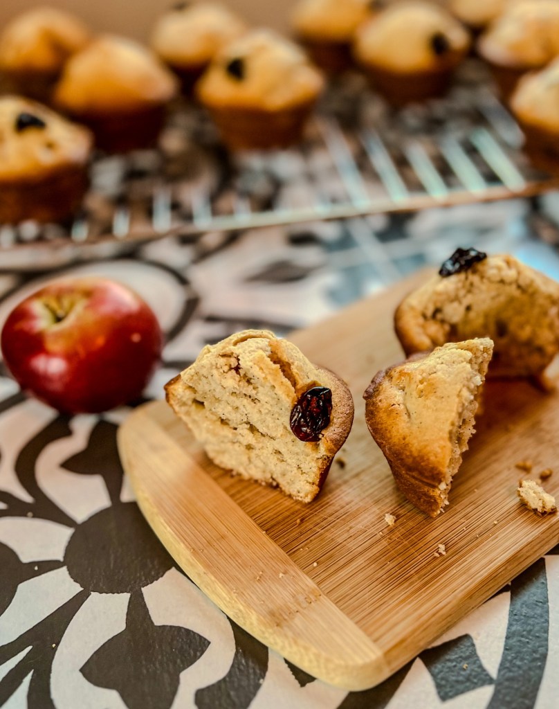 Apple cherry muffins on a baking rack with a muffin sliced in half right in front