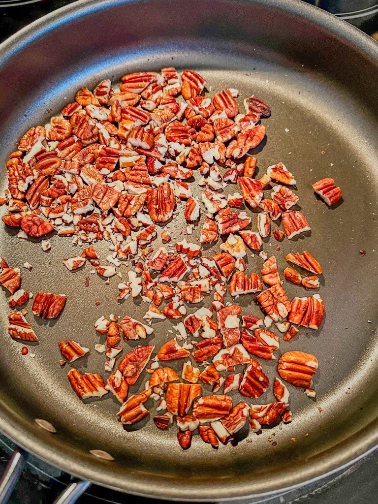 Pecans being toasted in a frying pan