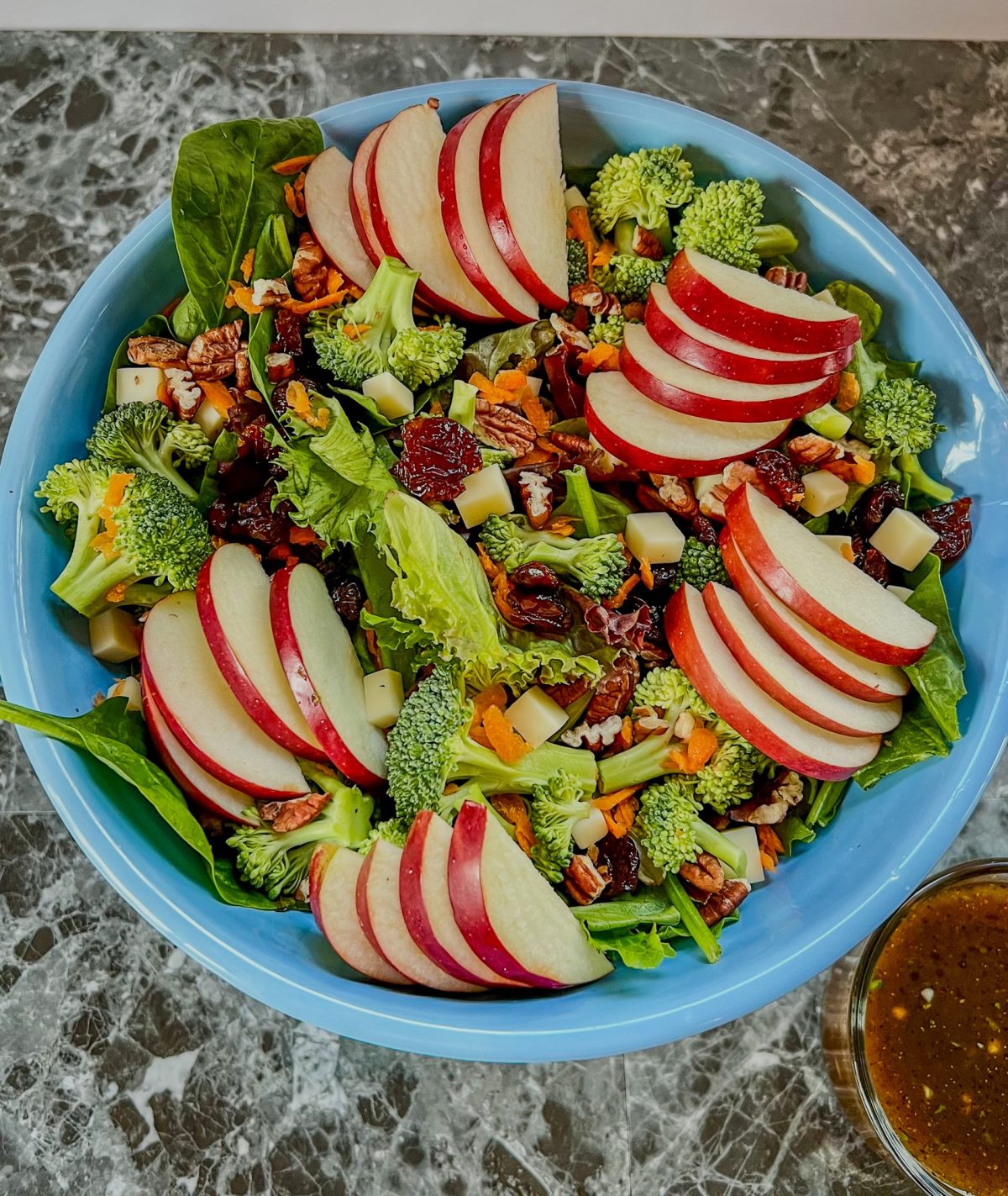Apple salad in a bowl with some honey balsamic vinaigrette in a dish off to the side