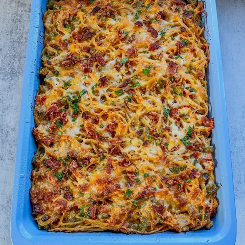 Baked chicken spaghetti fresh out of the oven with parsley and bacon for garnish