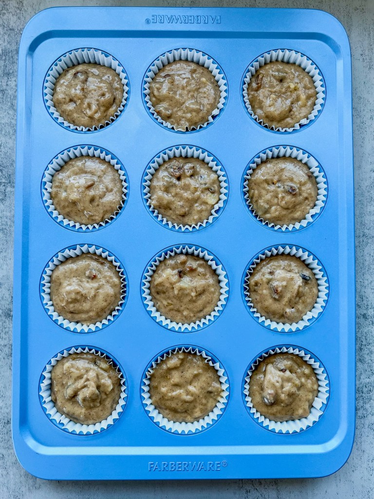 Banana walnut cupcake batter in some cupcake liners in a muffin pan just before going into the oven.