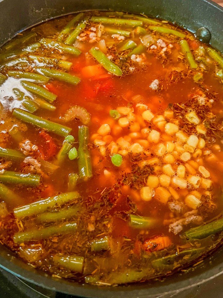 A big pot of vegetable soup cooking on the stove