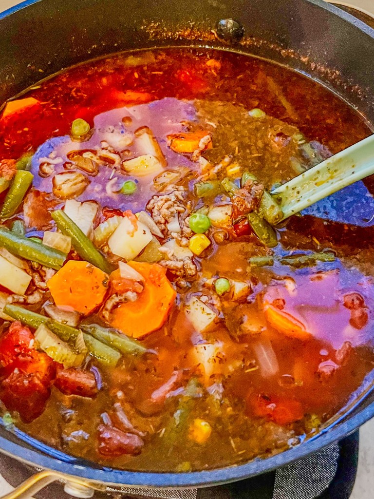 Beefy vegetable soup in a large stockpot with a serving spoon inside