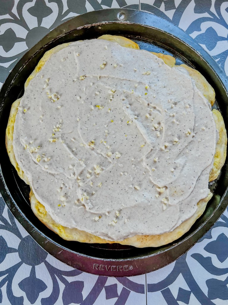 Par-baked pizza dough with white gravy and fresh garlic
