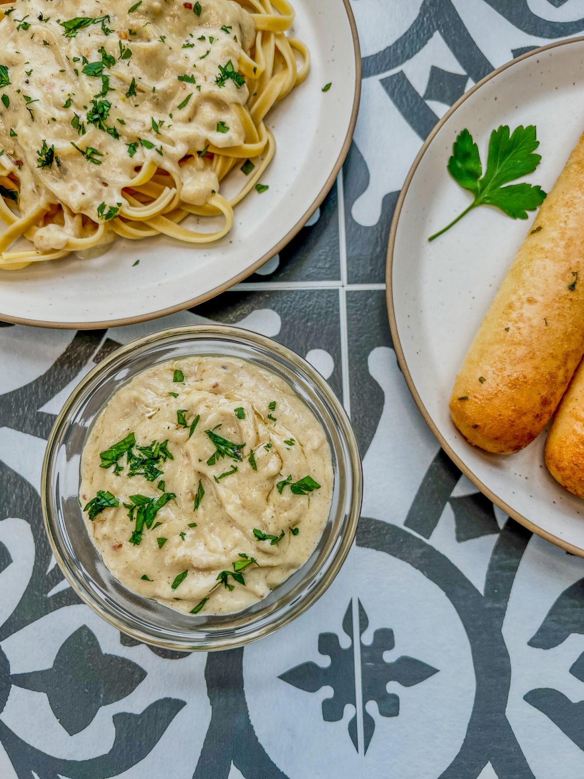 Brown butter alfredo sauce in a dish with some breadsticks and a plate of fettuccine off to the side