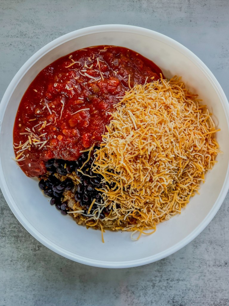 Filling ingredients for burrito bake in a large mixing bowl before being stirred