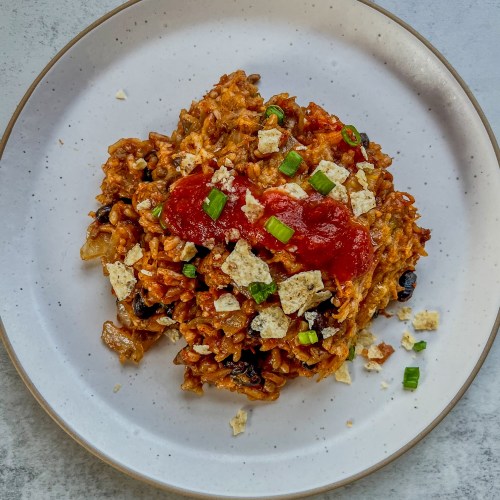 Burrito Bake on a white plate with a fork next to it on a countertop