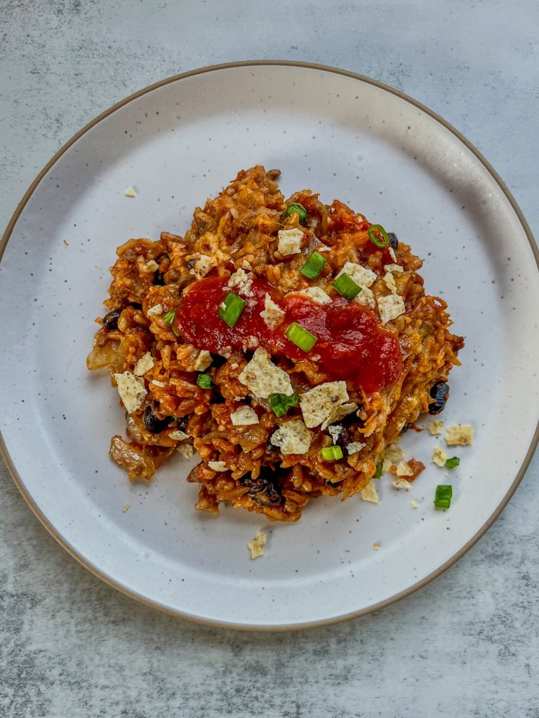 Burrito Bake on a white plate with a fork next to it on a countertop