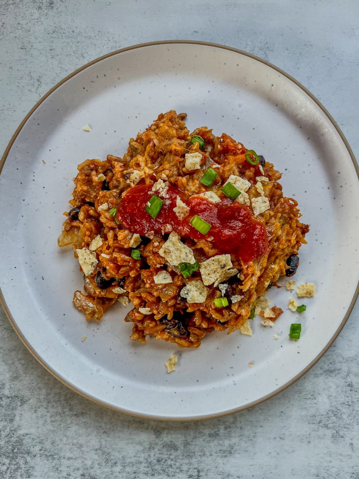 Burrito Bake on a white plate with a fork next to it on a countertop