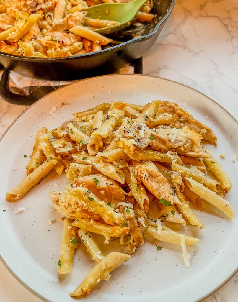 Chicken Marsala Bake on a white plate with a pan filled with more behind