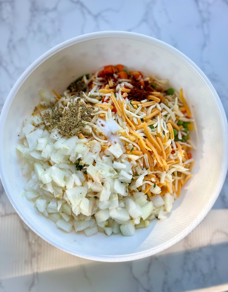 A bowl filled with the filling for chicken noodle casserole before it's been stirred on a marble counter
