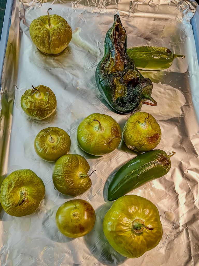 Roasted peppers and tomatillos on a baking sheet