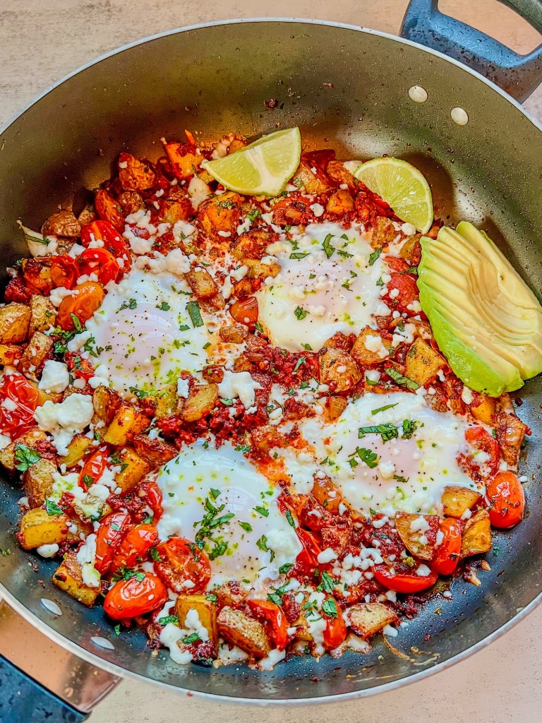 Chorizo Hash with queso fresco, cilantro, avocado, and lime wedges garnished on top