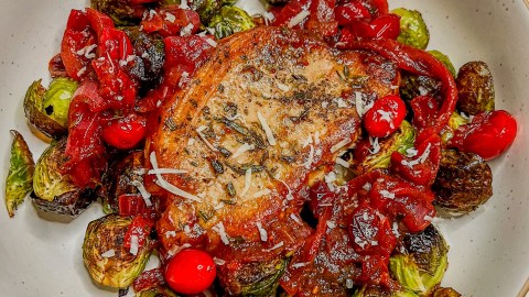 Cranberry onion pork chops with roasted brussels sprouts on a white plate