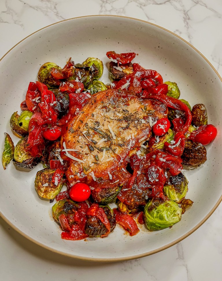 Cranberry onion pork chops with roasted brussels sprouts on a white plate