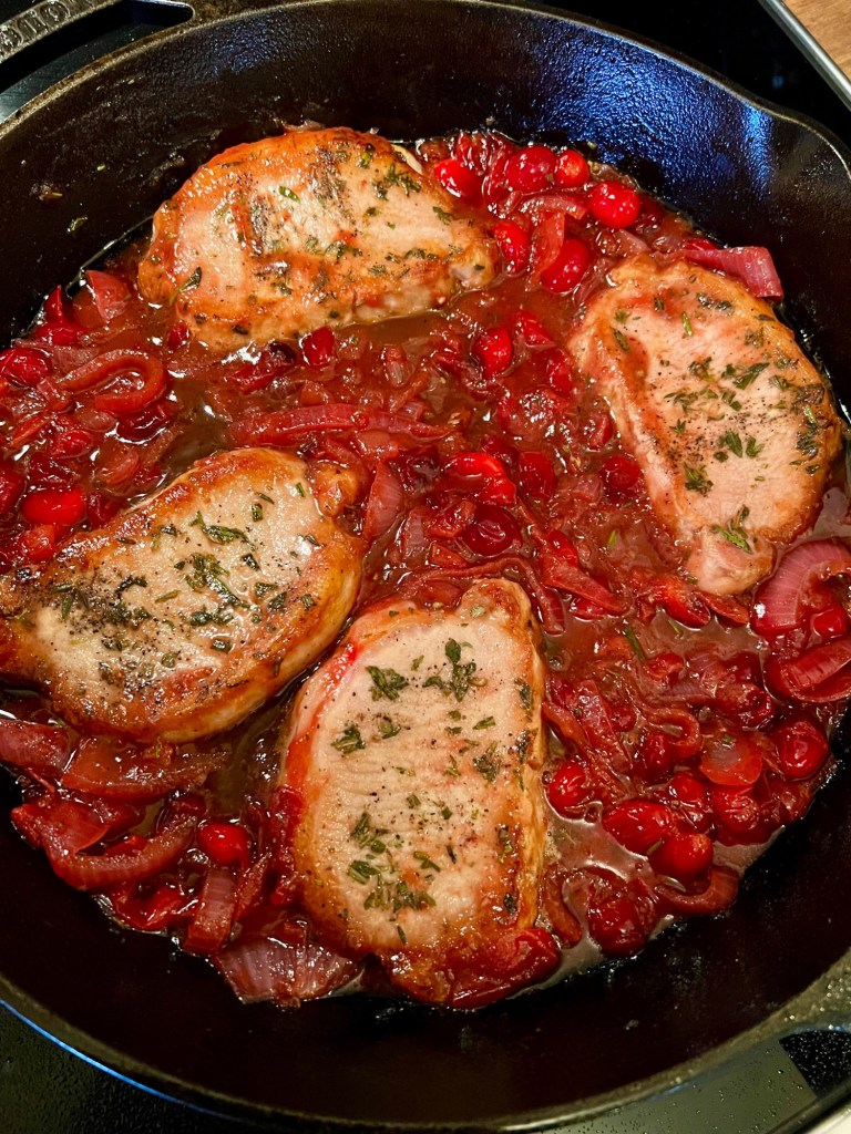 Cranberry onion pork chops in a cast iron skillet