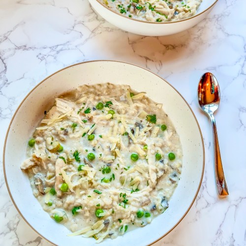 Crockpot creamy chicken and rice soup in a bowl with a spoon next to it and another bowl behind