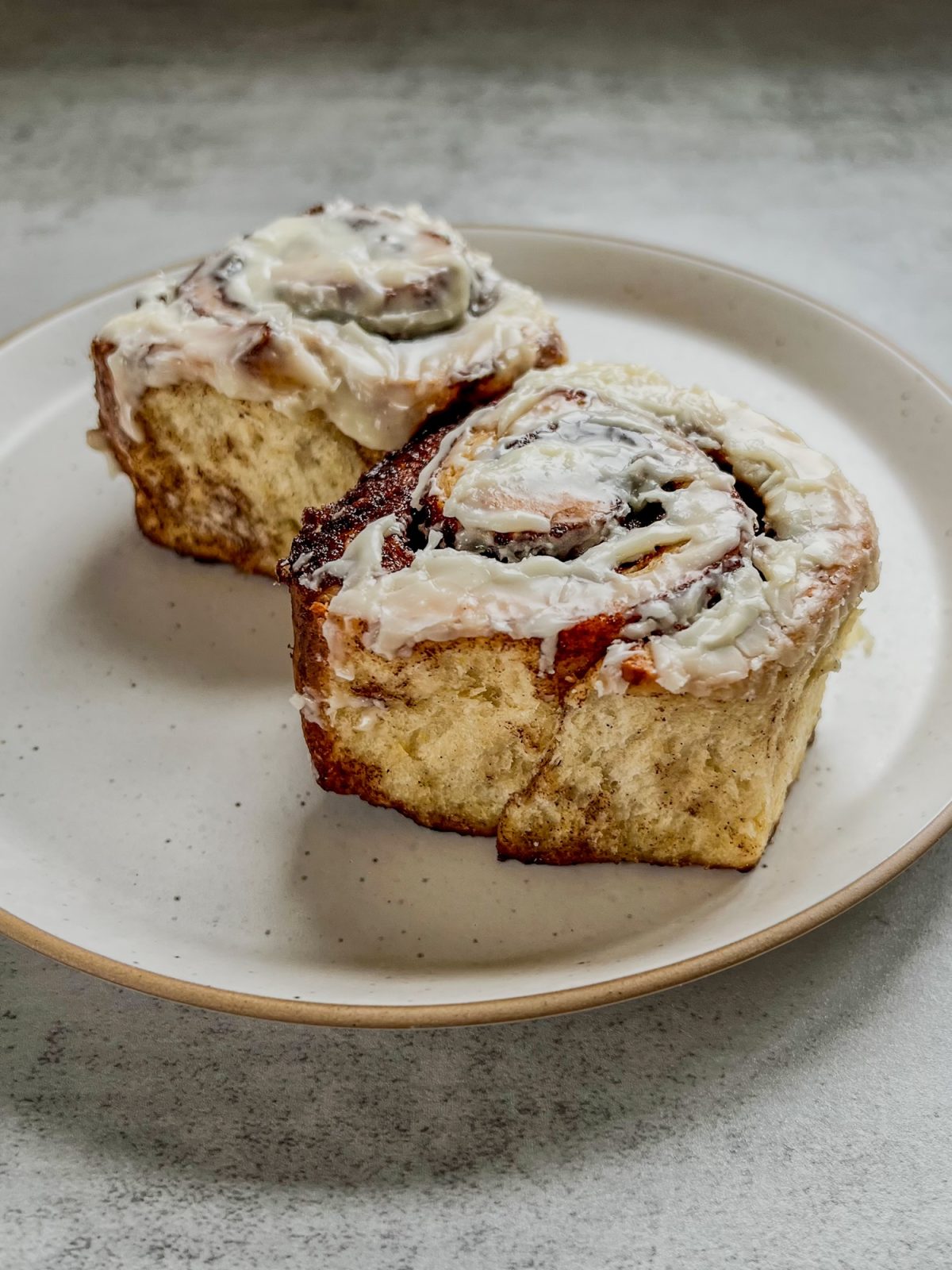 Eggnog cinnamon rolls with eggnog icing on a white plate