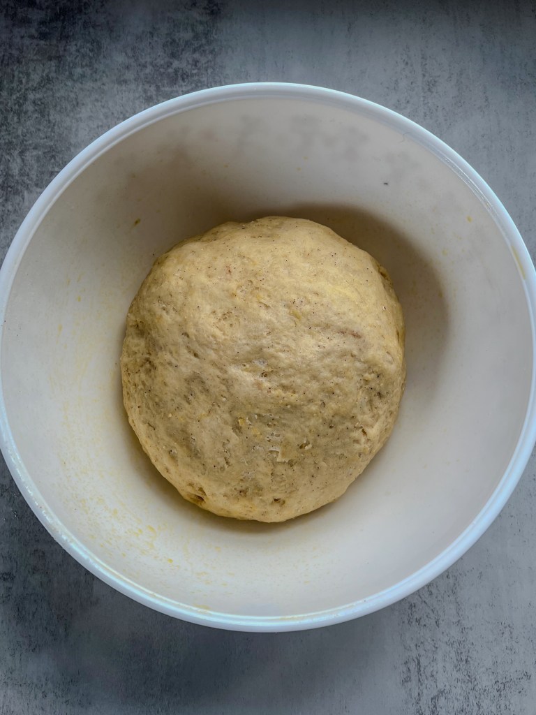 A dough ball that has doubled in size inside a large mixing bowl on a countertop