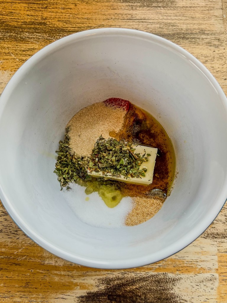 Garlic and herb spice butter ingredients in a mixing bowl on a wooden table